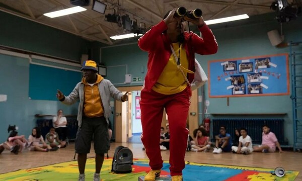 Performer with binoculars in school hall